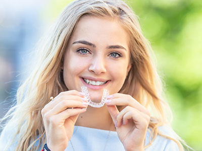 A young woman with braces is smiling at the camera.