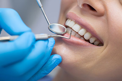 A woman undergoing dental treatment with a dentist using a drill on her teeth.