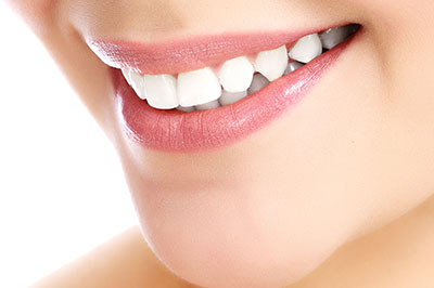 The image shows a close-up of a person s smiling face with white teeth, emphasizing their oral hygiene and dental health.