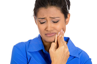 The image shows a woman with her eyes closed, looking upwards with a concerned expression, possibly indicating pain or discomfort, while holding her hand near her mouth.