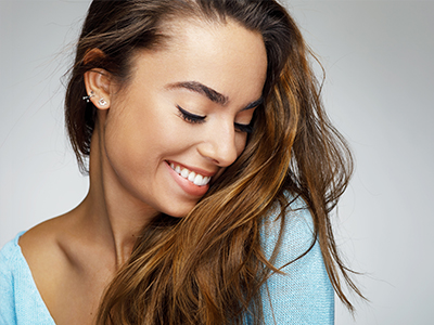 An advertisement featuring a woman with long hair smiling at the camera, set against a light background.