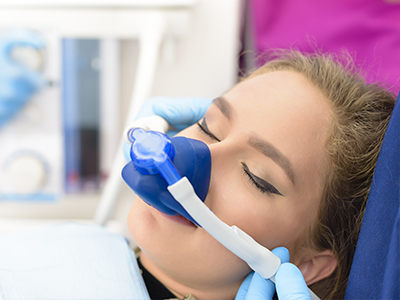 A woman receiving oxygen therapy from a medical device while being attended to by a healthcare professional.